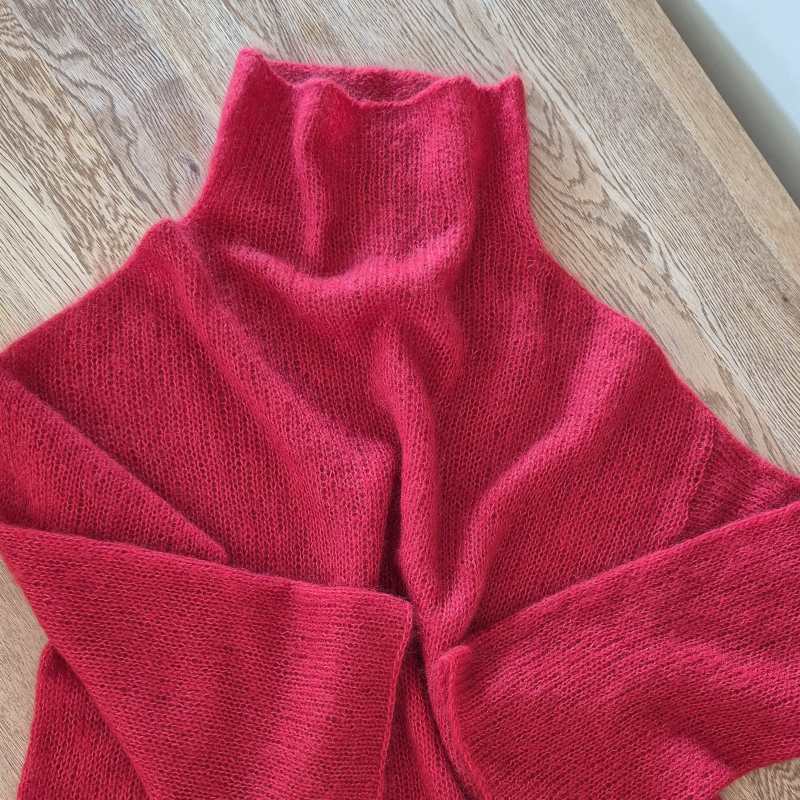 A red silk mohair sweater laying flat on a wooden surface.