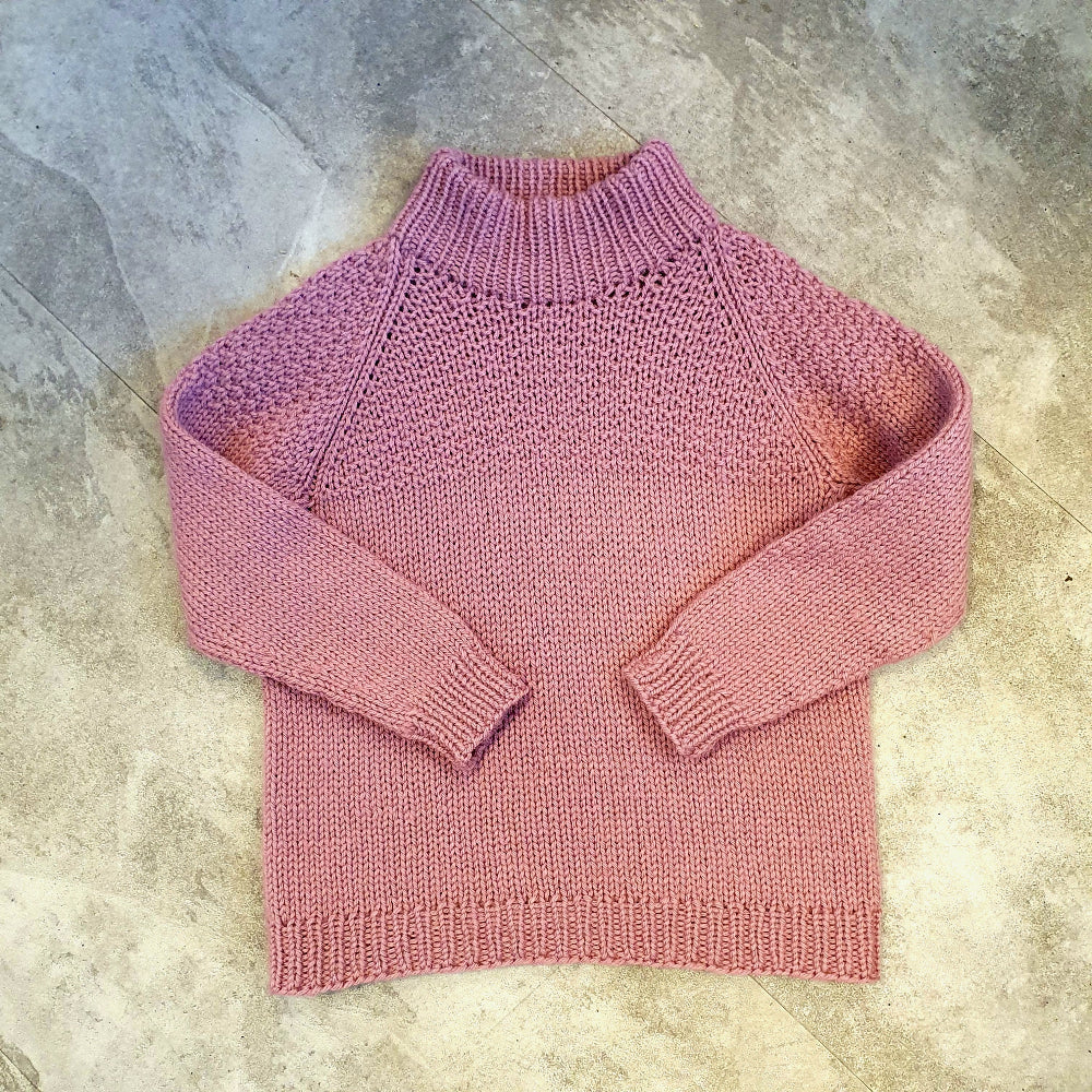 Pink knitted sweater on a textured surface