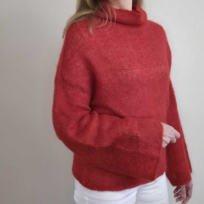 A woman wearing an elegant red, silk mohair, knitted sweater with a boxy fit and wide sleeves.