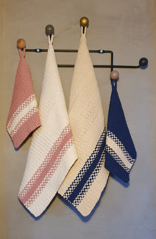 A set of knitted kitchen towels with textured stitch pattern in various colors hanging on a wall hook.